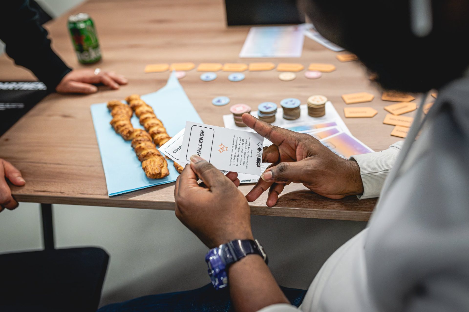 Hands holding Challenge cards with game pieces on table
