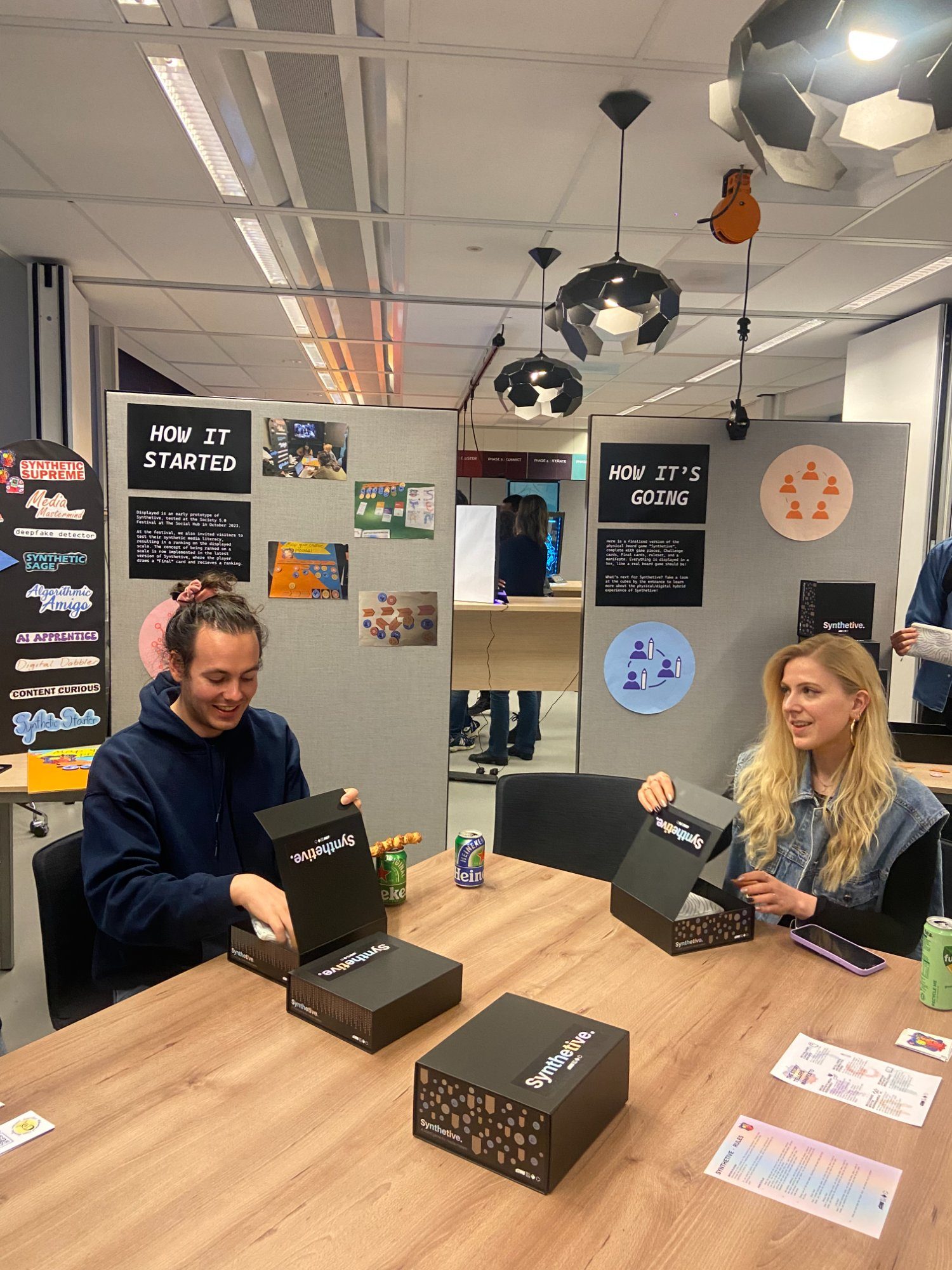 Two people opening Synthetive boxes with display boards visible